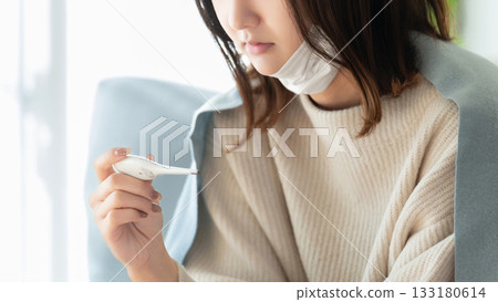 Unwell woman taking her temperature Unwell woman taking her temperature 133180614