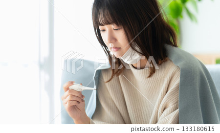 Unwell woman taking her temperature Unwell woman taking her temperature 133180615