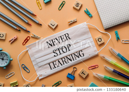 Face mask with motivational phrase surrounded by colorful stationery and learning materials 133180640