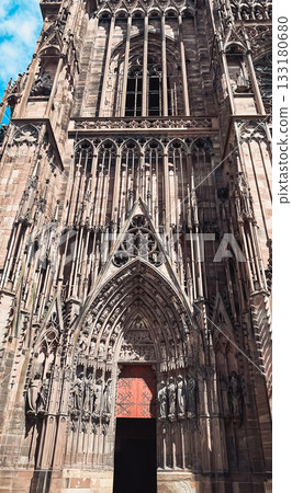 Majestic Gothic cathedral facade showcasing intricate stone carvings and towering spires 133180680