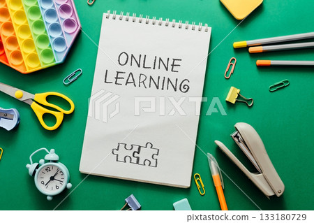 Online learning concept with stationery items and colorful educational tools on green background Online learning concept with stationery items and colorful educational tools on green background 133180729