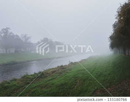 Foggy day with a river running through a grassy area Foggy day with a river running through a grassy area 133180766