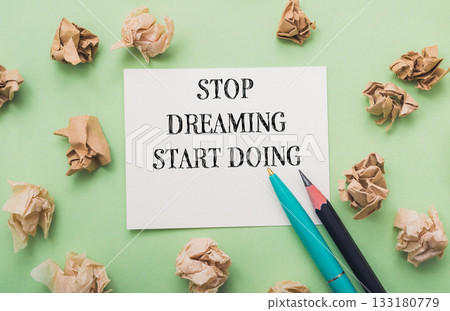 Piece of paper with the words Stop dreaming start doing written on it Piece of paper with the words Stop dreaming start doing written on it 133180779