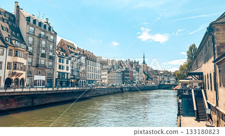 Scenic riverside view showcasing charming historic buildings along the waterway, with clear blue skies and reflections creating a serene atmosphere 133180823