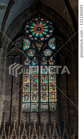 Stained glass window featuring intricate designs and vibrant colors, illuminating the interior of a historic cathedral with gothic architecture and spiritual ambiance 133180885