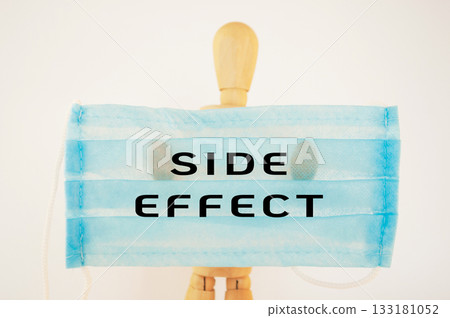 Man is holding a blue surgical mask with the words Side Effect written on it 133181052