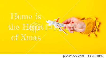 Hand holding airplane toy against vibrant yellow background, symbolizing holiday travel and joy Hand holding airplane toy against vibrant yellow background, symbolizing holiday travel and joy 133181092