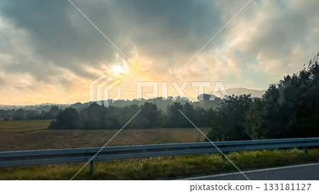 Scenic landscape with misty hills and dramatic sky during sunrise in a tranquil setting Scenic landscape with misty hills and dramatic sky during sunrise in a tranquil setting 133181127