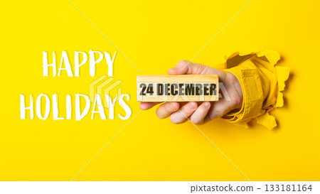 Hand holding wooden block with date 24 December against vibrant yellow background with text Hand holding wooden block with date 24 December against vibrant yellow background with text 133181164