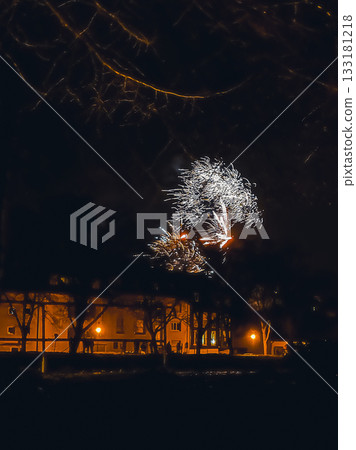 Colorful fireworks display illuminating night sky over urban landscape with glowing streetlights 133181218