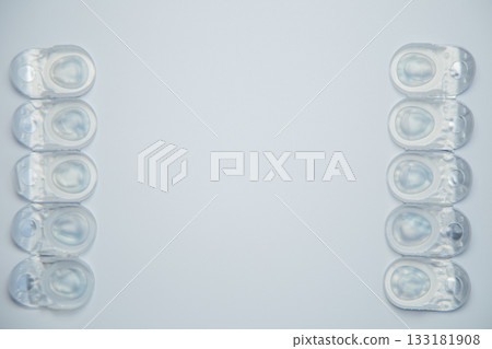 Daily disposable contact lenses in a disposable protective case lie in rows on the sides on a white background with space for text in the center. The concept of ophthalmology, vision correction, eye 133181908