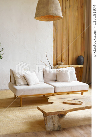 Modern minimalist interior of living room with beige sofa, rustic wooden table in natural light 133181974