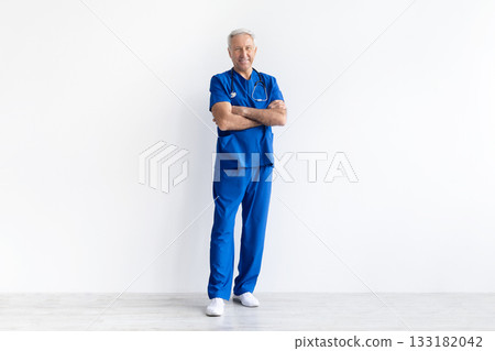 Senior male doctor in uniform standing with arms crossed on white background 133182042