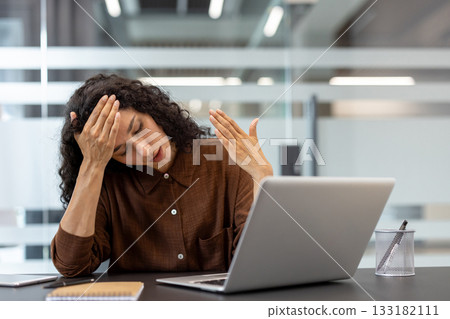 Young woman working from home experiencing a severe headache and burnout, feeling overwhelmed and frustrated by her work in a modern office environment Young woman working from home experiencing a severe headache and burnout, feeling overwhelmed and frustrated by her work in a modern office environment 133182111