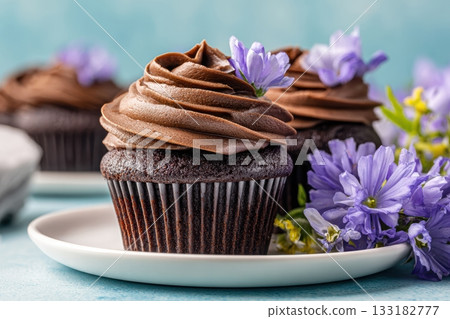 Delicious chocolate cupcakes with flowers on a plate Delicious chocolate cupcakes with flowers on a plate 133182777