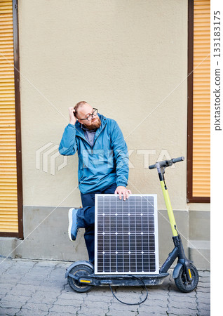 Male person holds photovoltaic solar panel, for charging electric scooter in urban settings. Integration of solar power as sustainable energy source, promoting eco-friendly urban transportation. Male person holds photovoltaic solar panel, for charging electric scooter in urban settings. Integration of solar power as sustainable energy source, promoting eco-friendly urban transportation. 133183175
