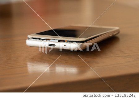 一部手機,電池鼓包,放在桌上。 一部手機,電池鼓包,放在桌上。 133183242