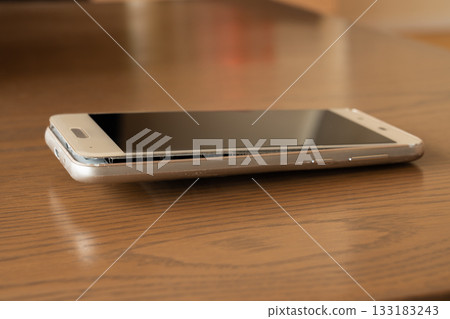 A smartphone with a swollen mobile battery placed on a table 133183243