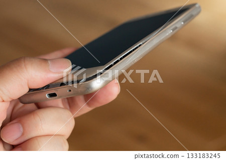 Man holding smartphone with swollen mobile battery 133183245
