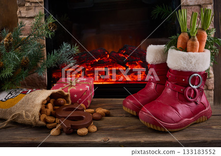 Saint Nicholas - Sinterklaas shoe with carrot and sweets near the fireplace 133183552