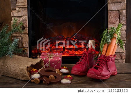 Saint Nicholas - Sinterklaas shoe with carrot and sweets near the fireplace 133183553