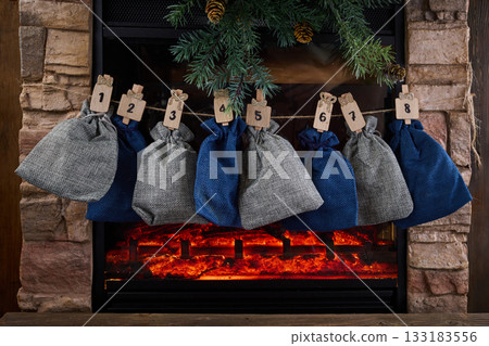 Cozy Advent Calendar. A cozy fireplace scene with numbered advent bags Cozy Advent Calendar. A cozy fireplace scene with numbered advent bags 133183556