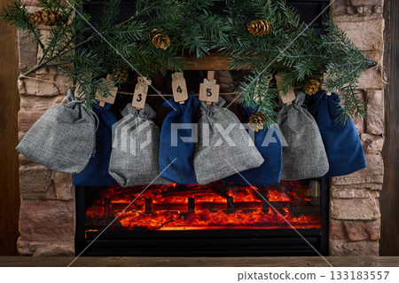 Cozy Advent Calendar. A cozy fireplace scene with numbered advent bags Cozy Advent Calendar. A cozy fireplace scene with numbered advent bags 133183557