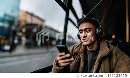 Smartphones as means of communicating with world and creating personal space urban environment, native American man with smartphone and headphones smiles while listening to music on his way to work Smartphones as means of communicating with world and creating personal space urban environment, native American man with smartphone and headphones smiles while listening to music on his way to work 133183659