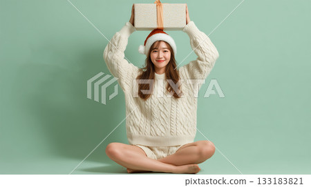 A woman sits on the floor and holds up a box A woman sits on the floor and holds up a box 133183821