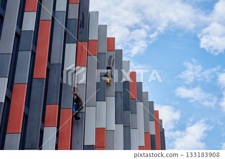 High rise workers cleaning windows on modern building facade High rise workers cleaning windows on modern building facade 133183908