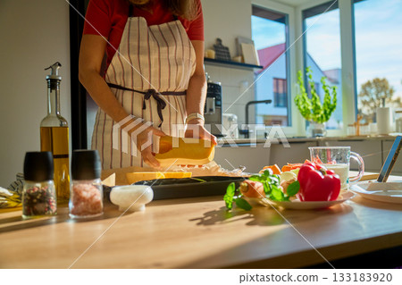 Woman preparing pumpkin for baking in home kitchen Woman preparing pumpkin for baking in home kitchen 133183920