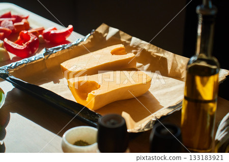 Halved pumpkin on baking tray with parchment paper before roasting Halved pumpkin on baking tray with parchment paper before roasting 133183921