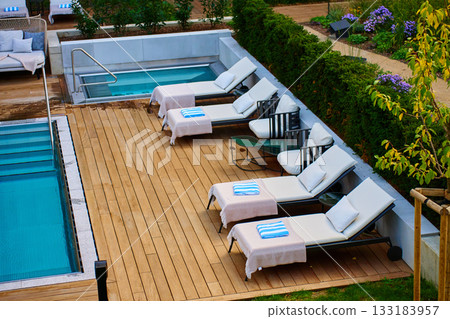 Outdoor pool area with lounge chairs and towels on wooden deck in hotel Outdoor pool area with lounge chairs and towels on wooden deck in hotel 133183957