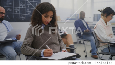 Young Woman in Good Mood Among Group Adult Students of Various Ages Completing Written Test 133184158