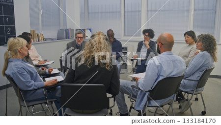 In Classroom With Large Windows and Chalkboard Schedule on Wall, Circle Adult Learners Listens 133184170