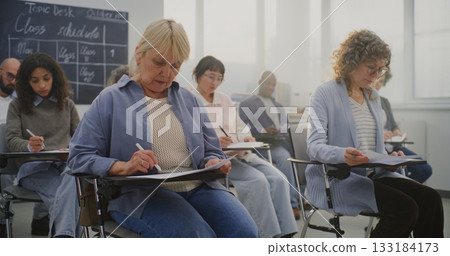 Mature Multicultural Students Attending Class, Taking Notes and Listening to Instructor 133184173