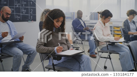 Mature Students Working on Assignments in Bright Contemporary Classroom Environment 133184177