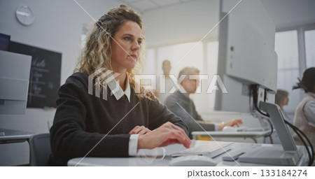 Curly Haired Woman Attends Coding Workshop, Looking at Screen, Smiling Warmly 133184274