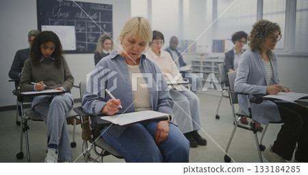 Multicultural Group Of Mature Students Taking Notes During Lesson in Bright Classroom 133184285