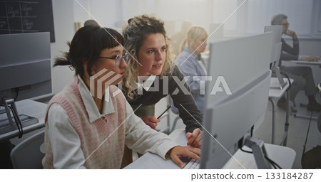 Confident Middle Aged Woman Instructor Supports Adult Female Learner in Computer Lab 133184287