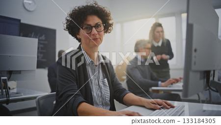 Dark Haired Woman in Her Mid Forties Sits at Monitor Coding During IT Class 133184305