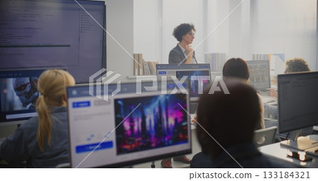 Female Teacher Stands By Large Screen Displaying Programming Code, Explaining Modeling Concepts Female Teacher Stands By Large Screen Displaying Programming Code, Explaining Modeling Concepts 133184321