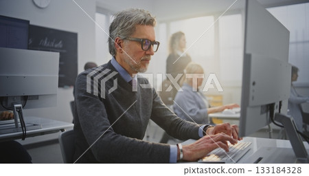 Stylish Senior Man With Glasses Works Attentively at Desktop Computer During Programming Course 133184328