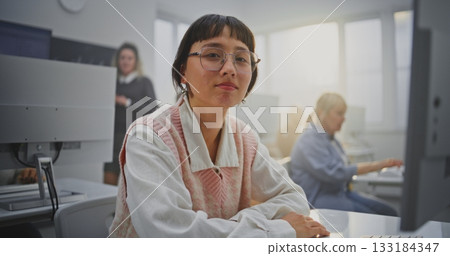 Focused on Screen Woman in Glasses Sits at Computer During Coding Class, Smiling 133184347