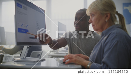 Elderly Woman Listens Attentively as Young Teacher Guides Through AI Prompt Creation on Computer 133184350