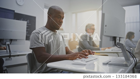 Cheerful Man Attends Programming Class, Smiling Brightly While Working on Computer 133184368