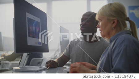 In Bright Modern Classroom, African American Instructor Helps Older Female Student Use AI Software 133184373