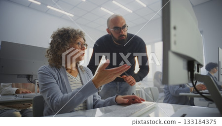 Middle Aged Female Student Works on Computer Project While Teacher Stands Beside 133184375
