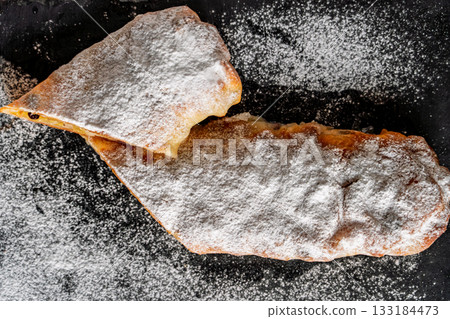 traditional German apple strudel with raisins and apples on a blackboard, with a top view of the cake dusted with powdered sugar, a favorite homemade treat for the Christmas holidays traditional German apple strudel with raisins and apples on a blackboard, with a top view of the cake dusted with powdered sugar, a favorite homemade treat for the Christmas holidays 133184473