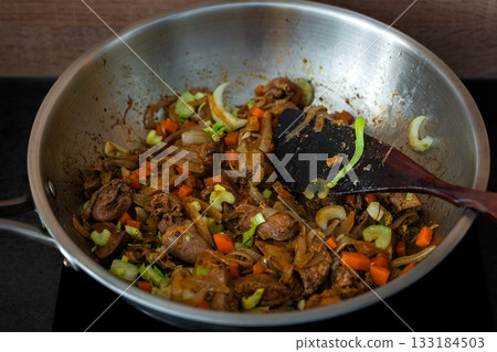 Preparing a warm chicken liver and celery salad at home, the ingredients in a steel skillet with olive oil and seasonings 133184503